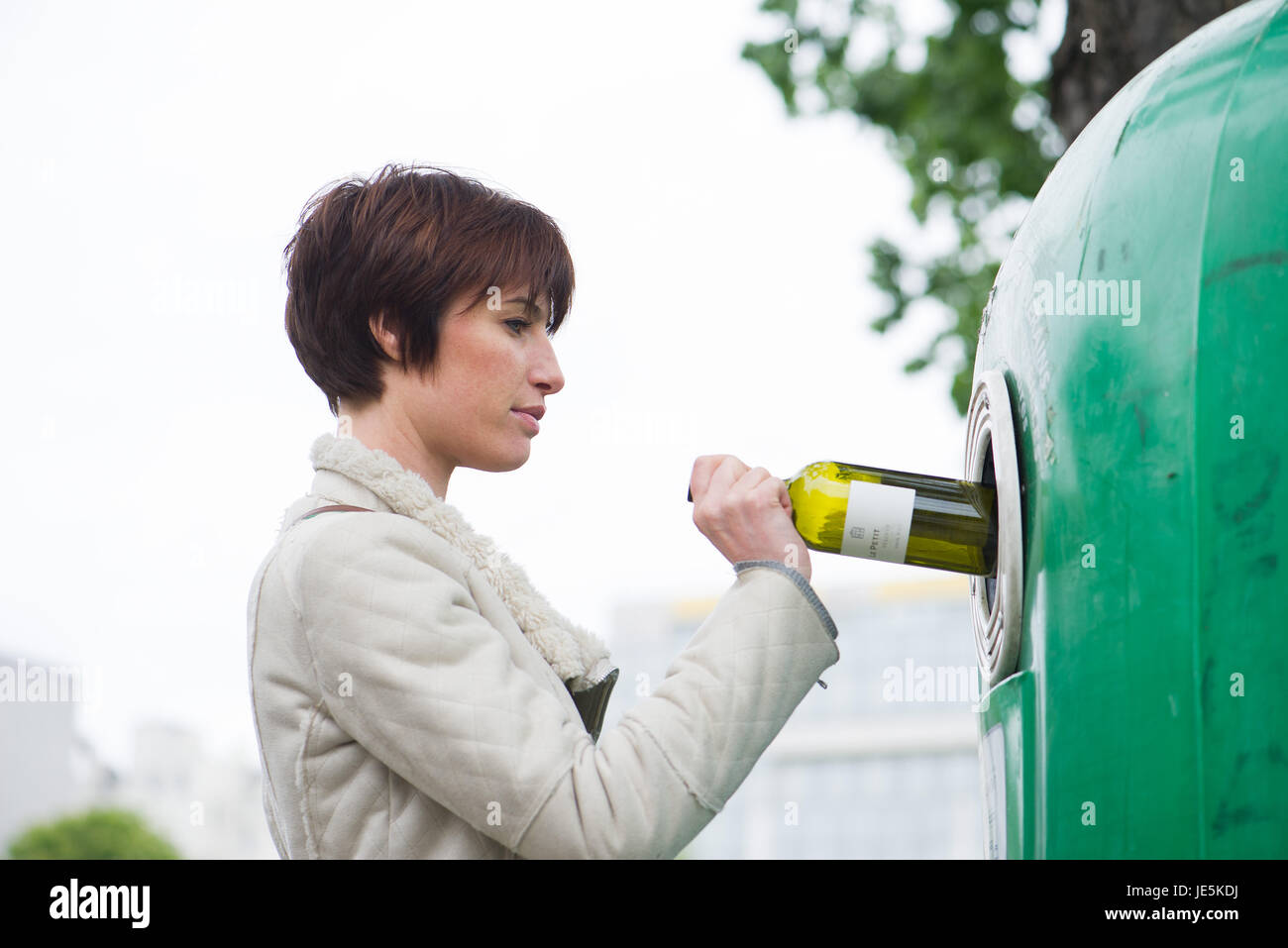 Woman putting wine bottle into recycling bin Stock Photo Alamy