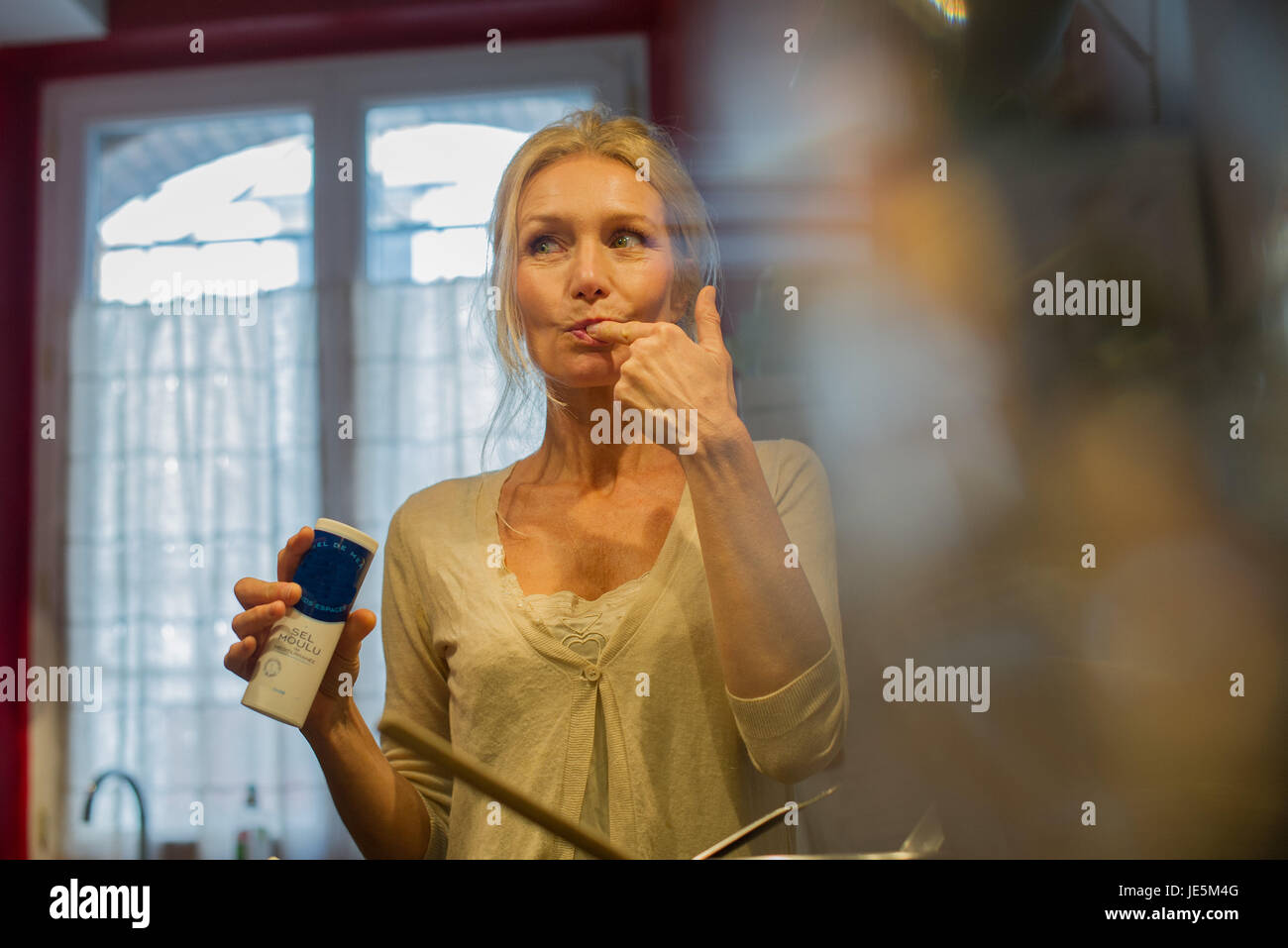 Mature woman tasting food while cooking Stock Photo