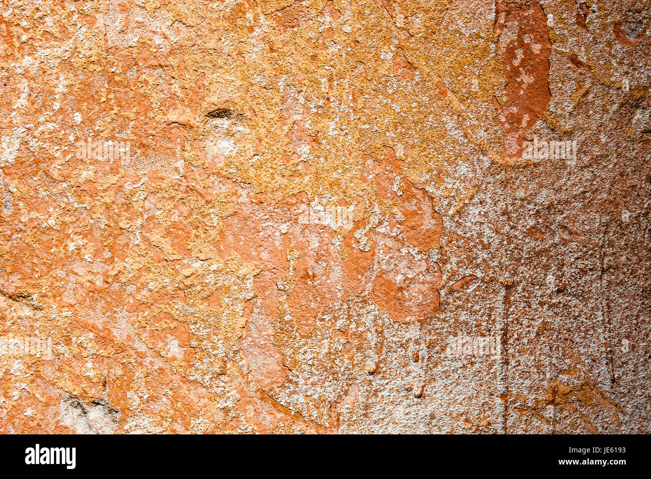 Concrete surface with the remains of orange paint and whitewash. Stock Photo