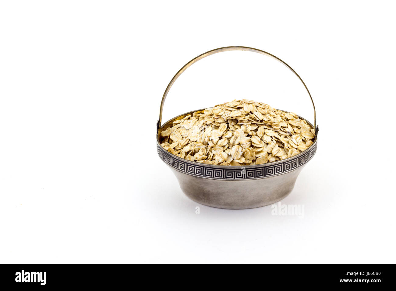 a silver bowl of uncooked rolled oats isolated on white background Stock Photo