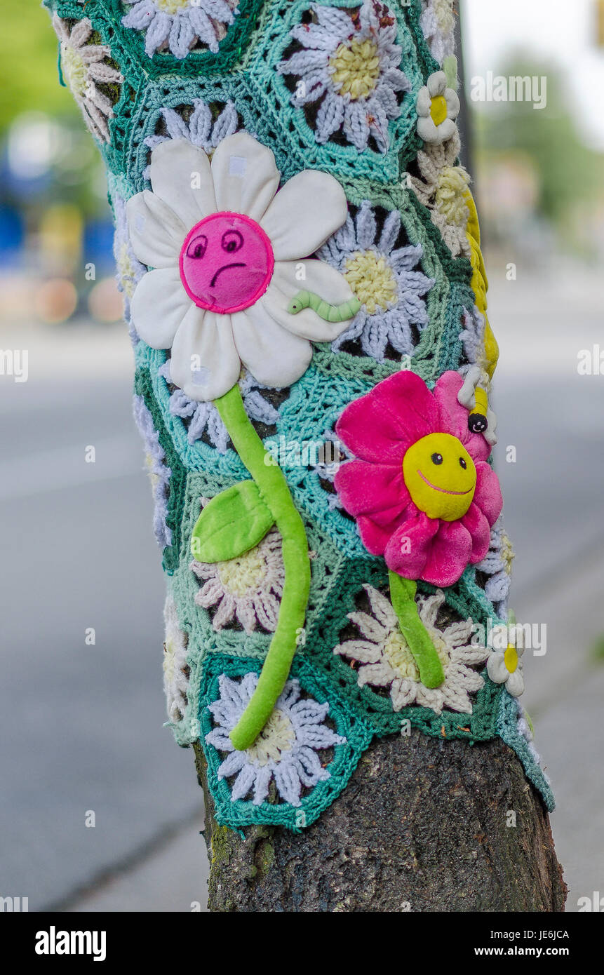 yarn bombing crochet flower sleeve on tree Stock Photo