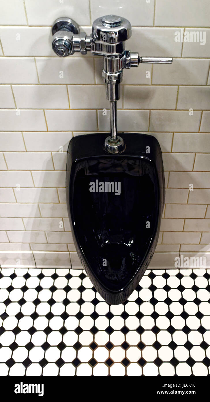 Modern clean black men's urinal. Black and white tile floor. Public restroom. Stock Photo