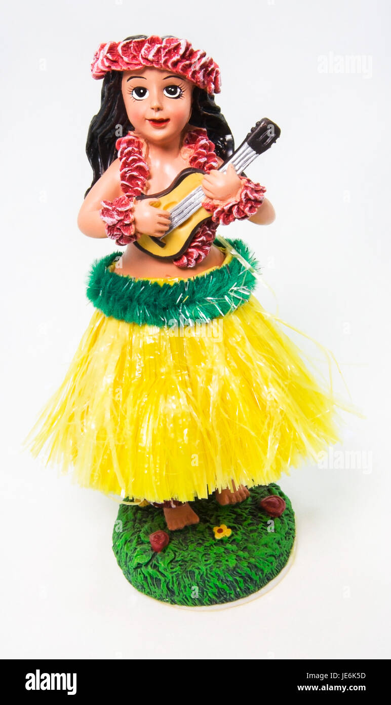Happy hula girl dashboard souvenir wearing grass skirt, flower leis, and holding ukulele. White background. Vertical. Stock Photo