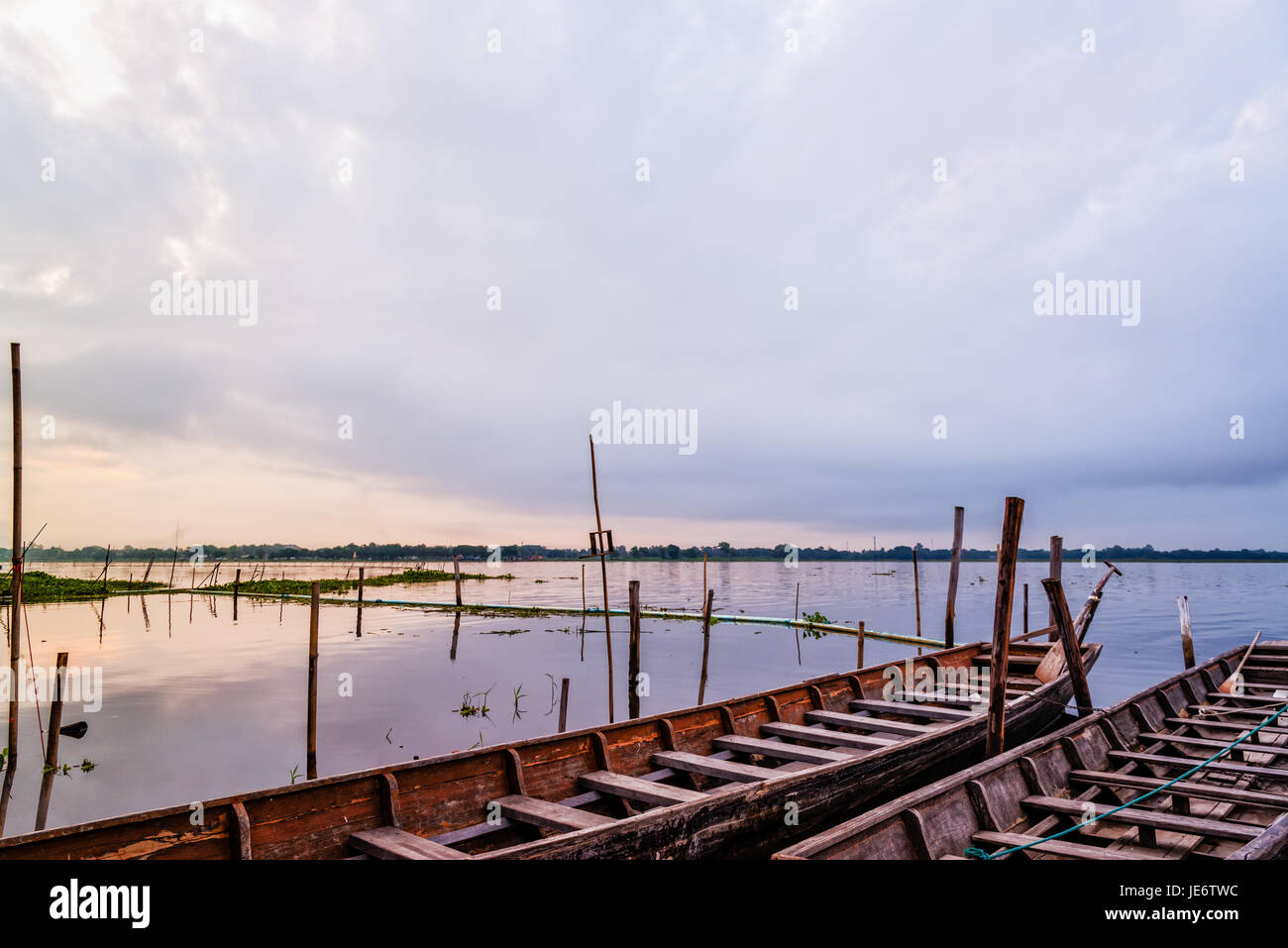 Old wooden boat floating on the water amidst the natural landscape of the morning at Kwan Phayao Lake in Phayao Province, Thailand Stock Photo