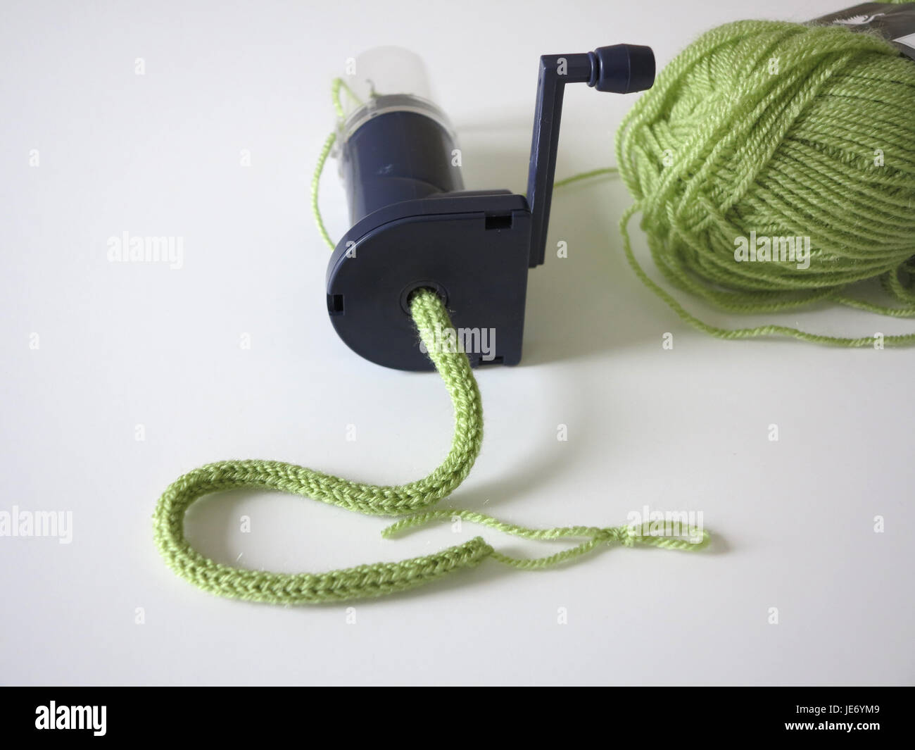 Plastic mechanical knitting mill with length of green wool knitted tube