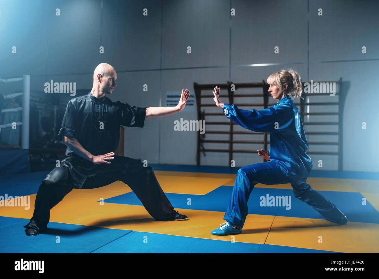 Male and female wushu fighters exercises indoor, martial arts. Sparring