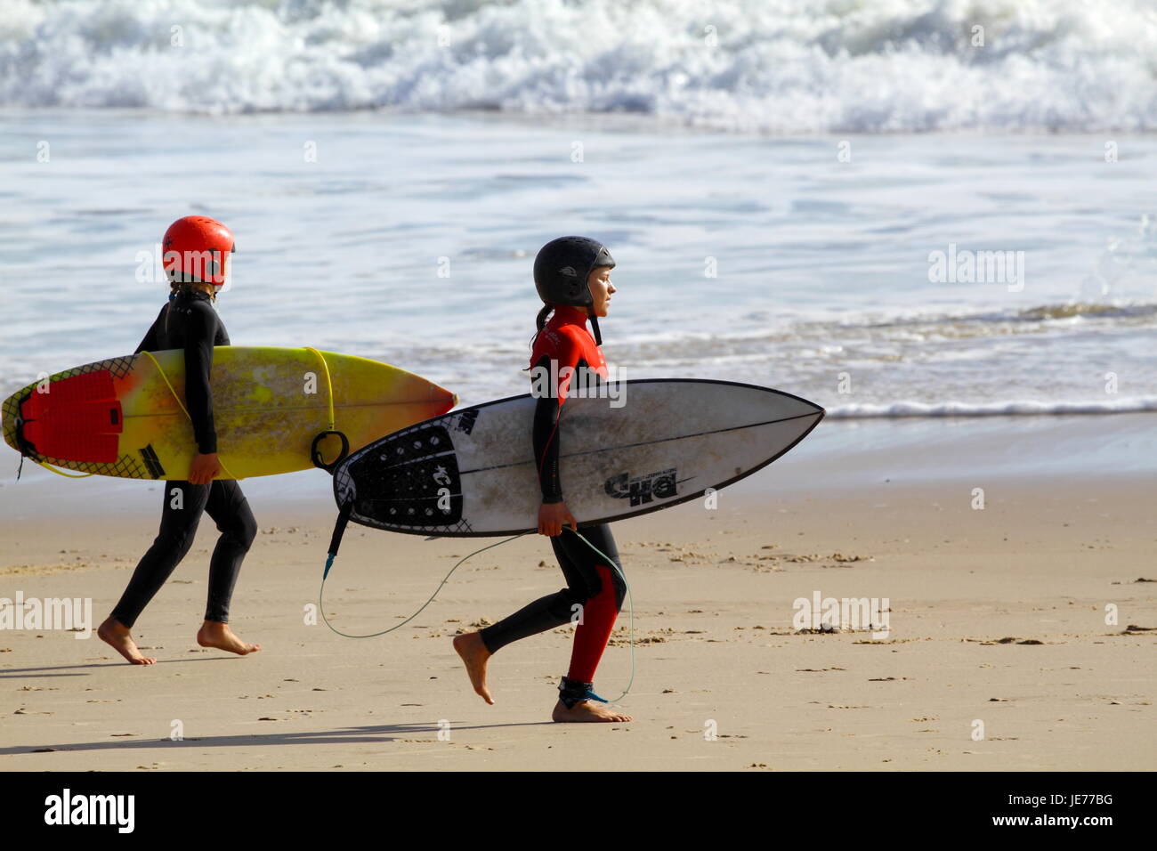 Two young preteen surfer girls going surfing Stock Photo
