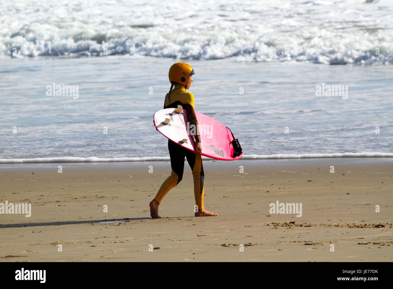 A young preteen surfer girl going surfing. Stock Photo