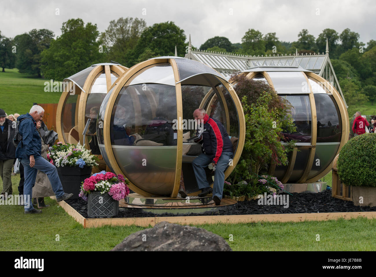 People visiting RHS Chatsworth Flower Show, Chatsworth House, Derbyshire, England, UK, enjoy looking round & trying out, modern spherical garden pods. Stock Photo