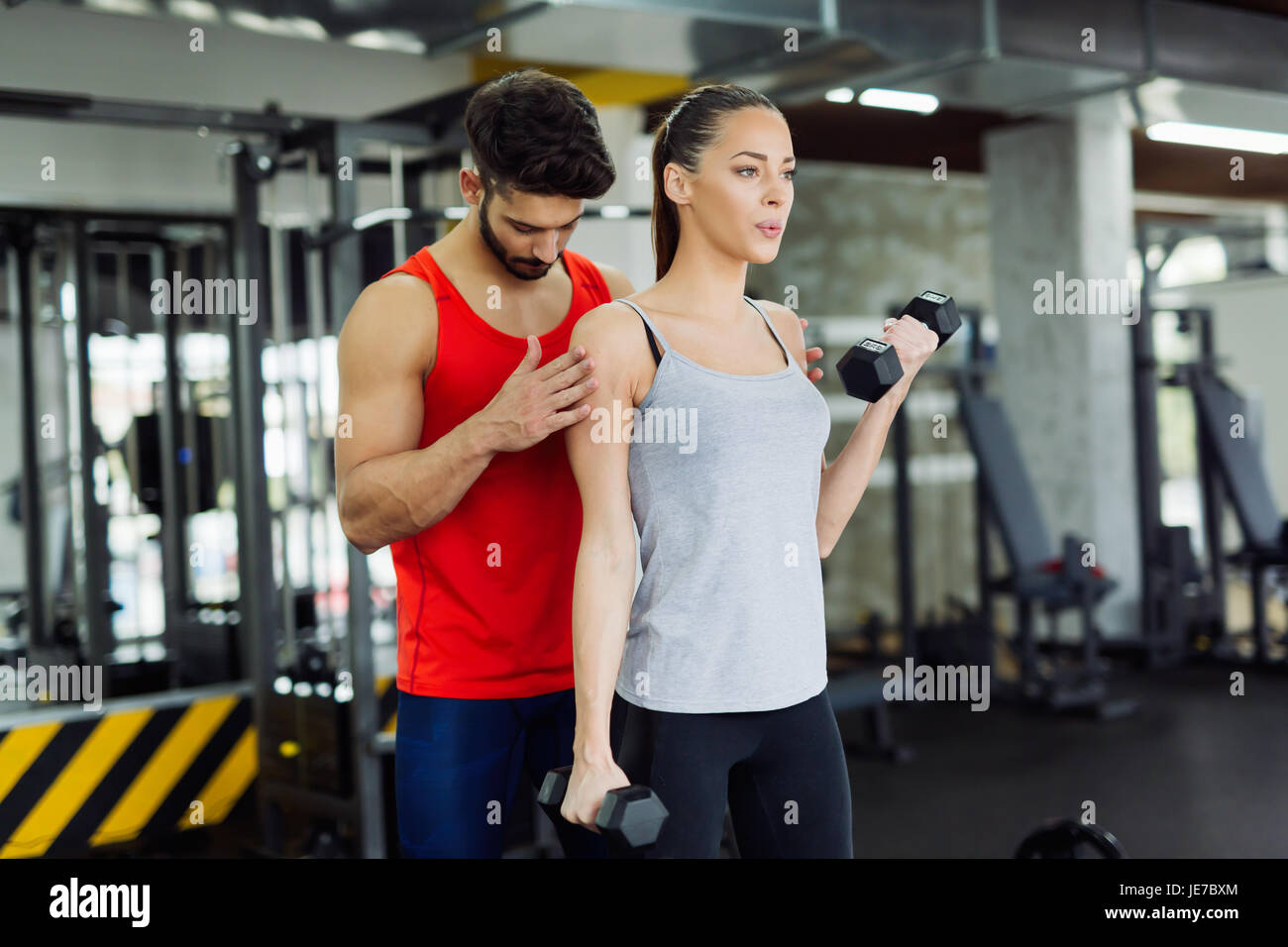 Young adult woman working out in gym with trainer Stock Photo