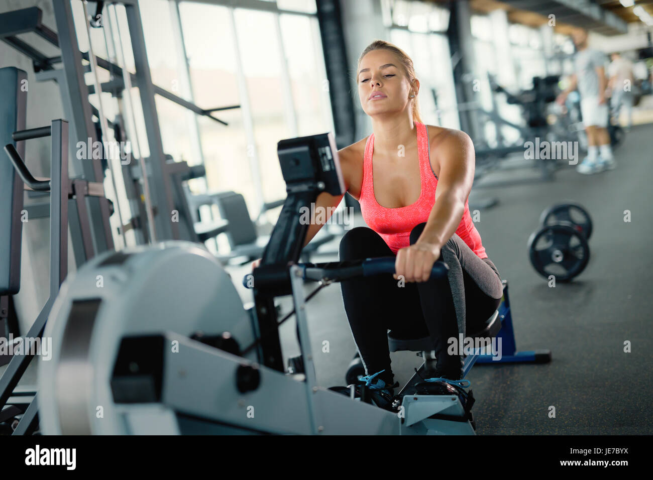 Young cute woman doing exercises with rowing machine Stock Photo