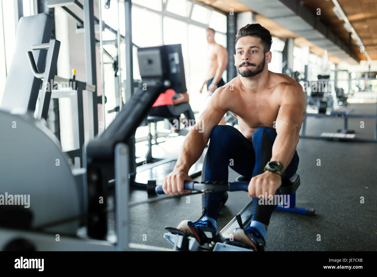 Young handsome man workout with rowing machine Stock Photo