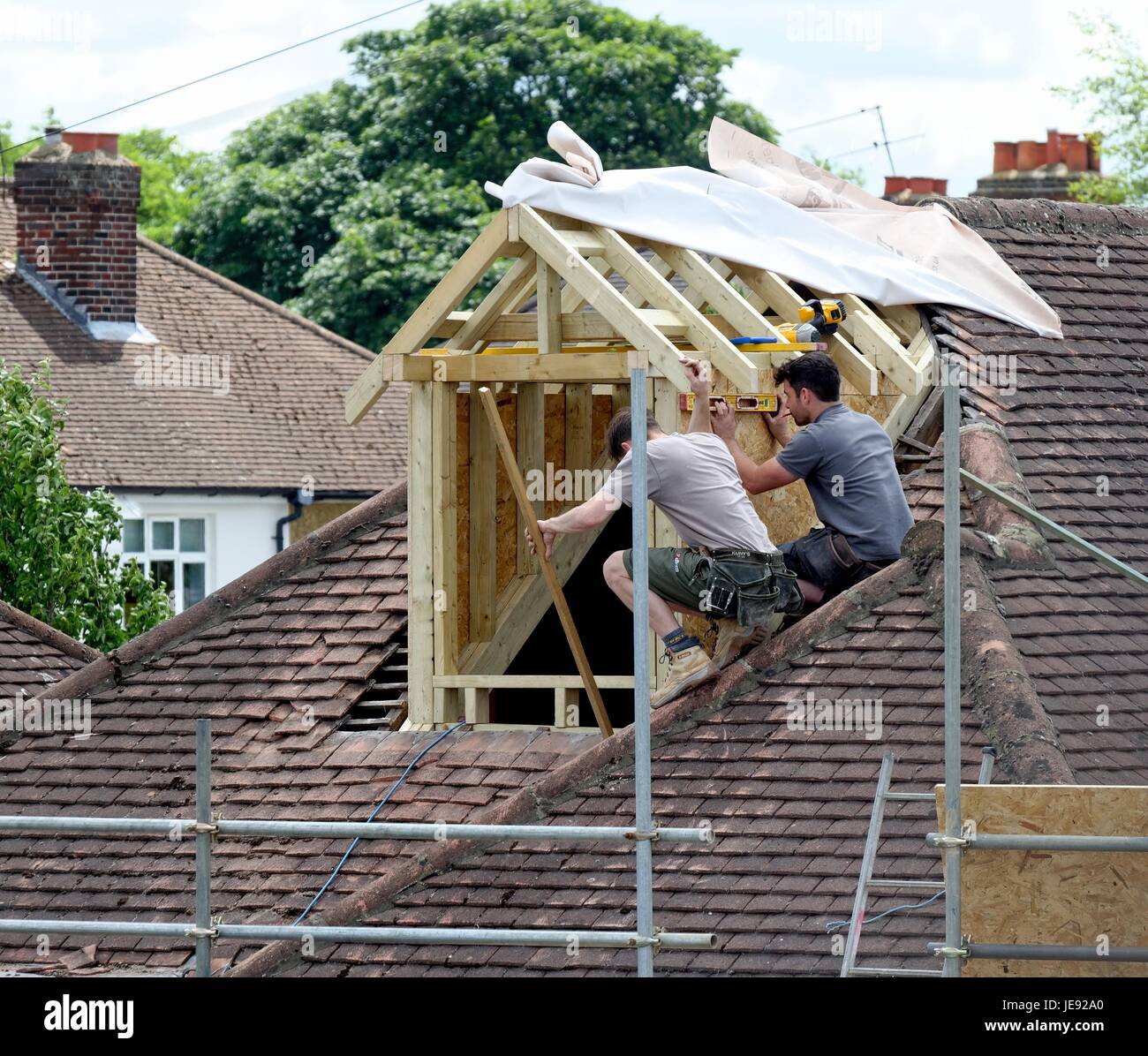 Builders constructing a loft extension on a suburban bungalow England UK Stock Photo