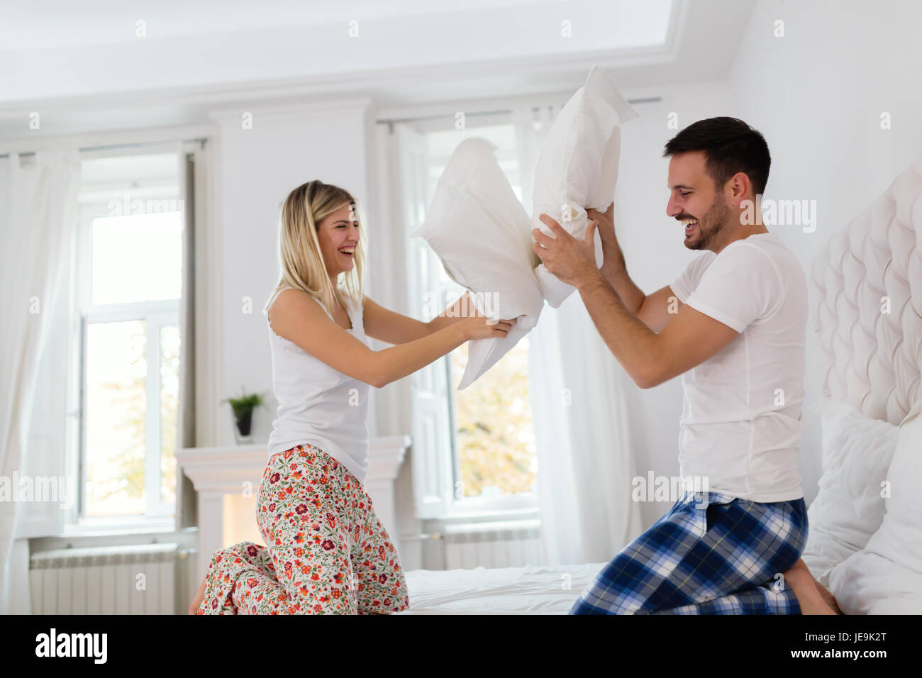 Happy couple fighting with pillows in bed Stock Photo