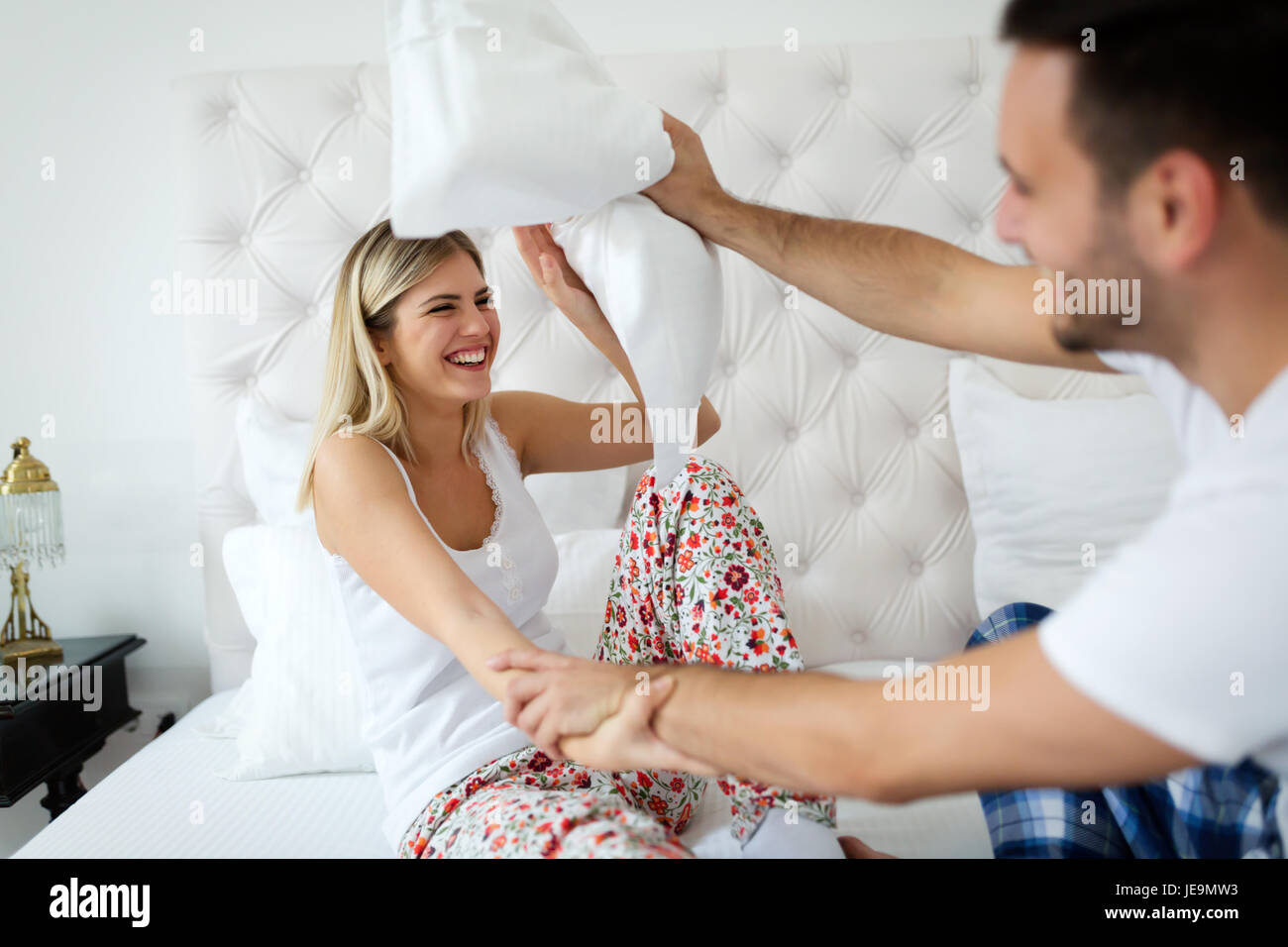 Happy attractive couple play fighting with pillows Stock Photo Alamy