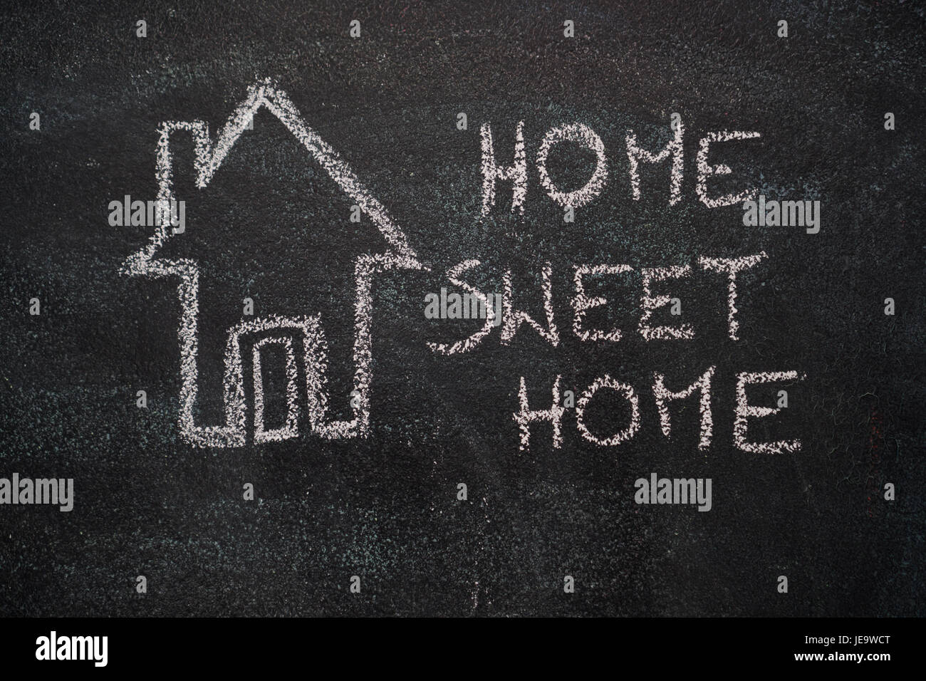 House with home sweet home writing drawn with white chalk on blackboard