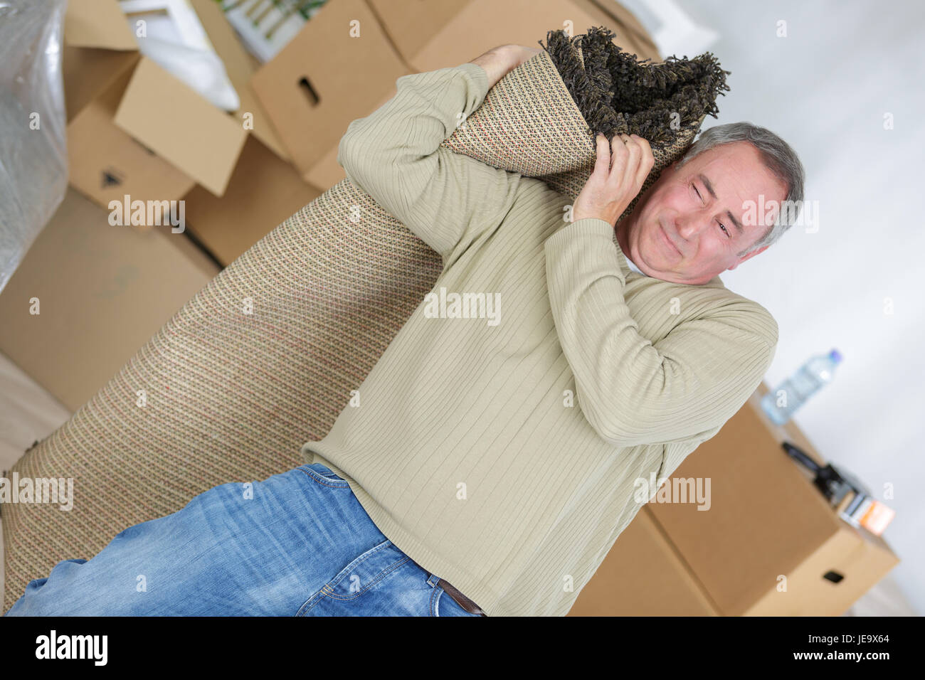 man carrying rolled carpet in living room Stock Photo Alamy