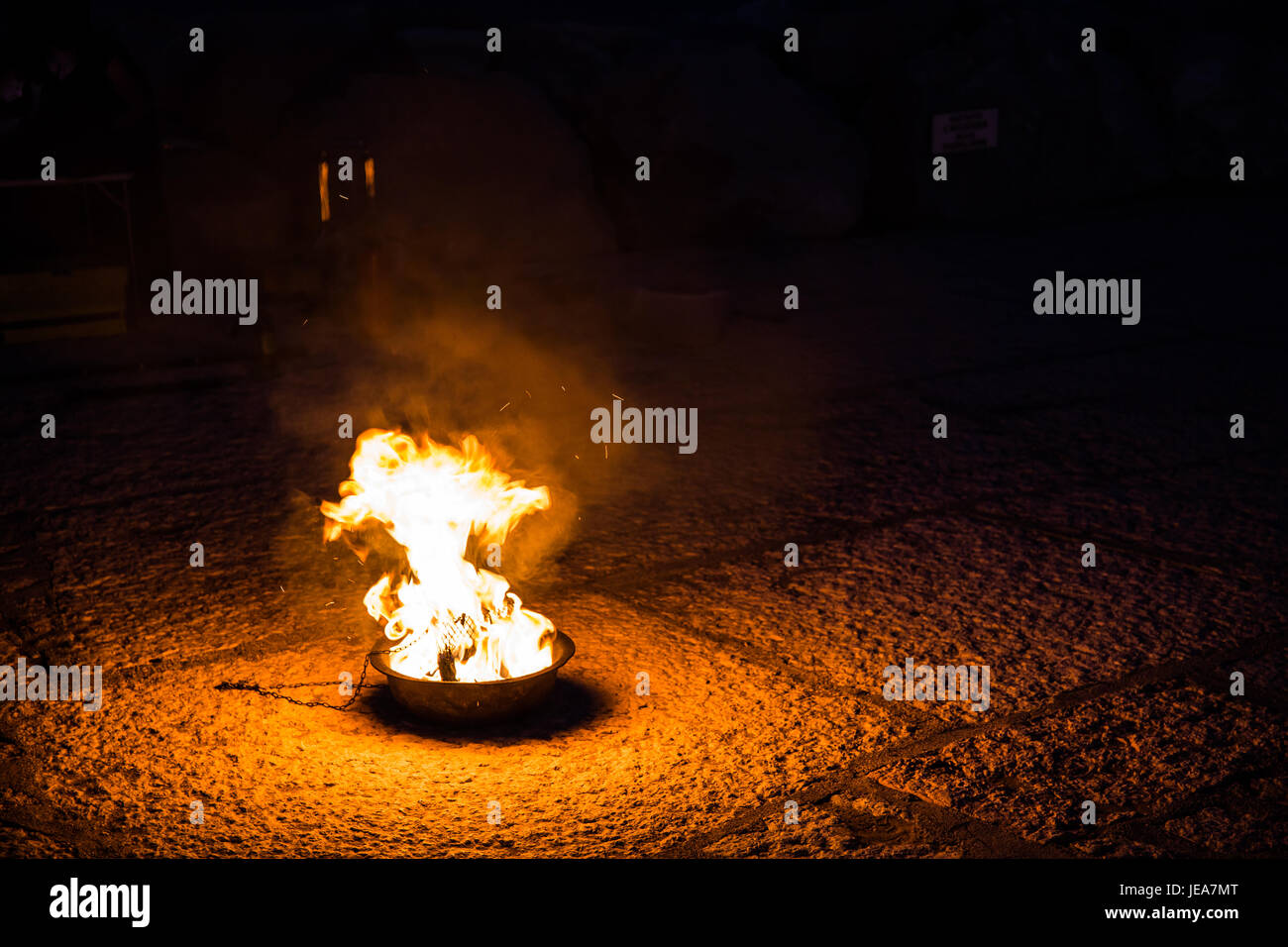 Ritual burning fire in a metal bowl on a stone pavement at night Stock