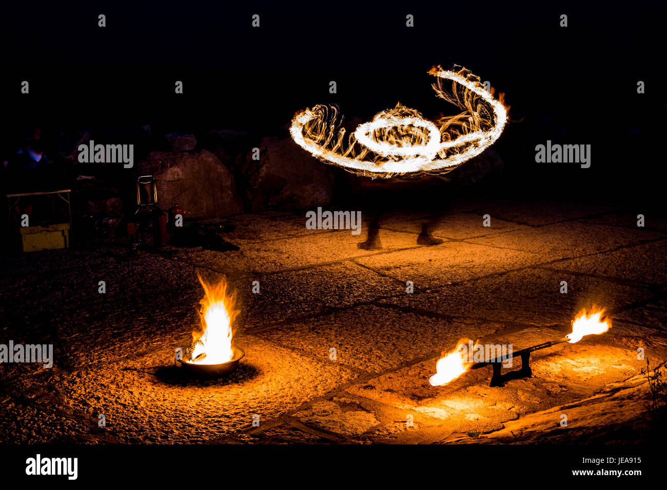 Street artist with a burning stick during his dangerous fire show Stock Photo