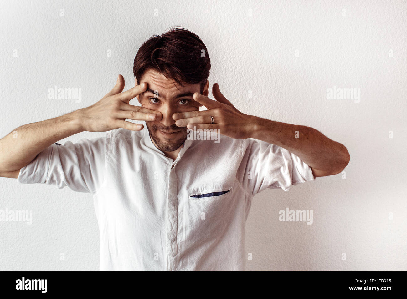 Businessman with hands over eyes look at camera Stock Photo