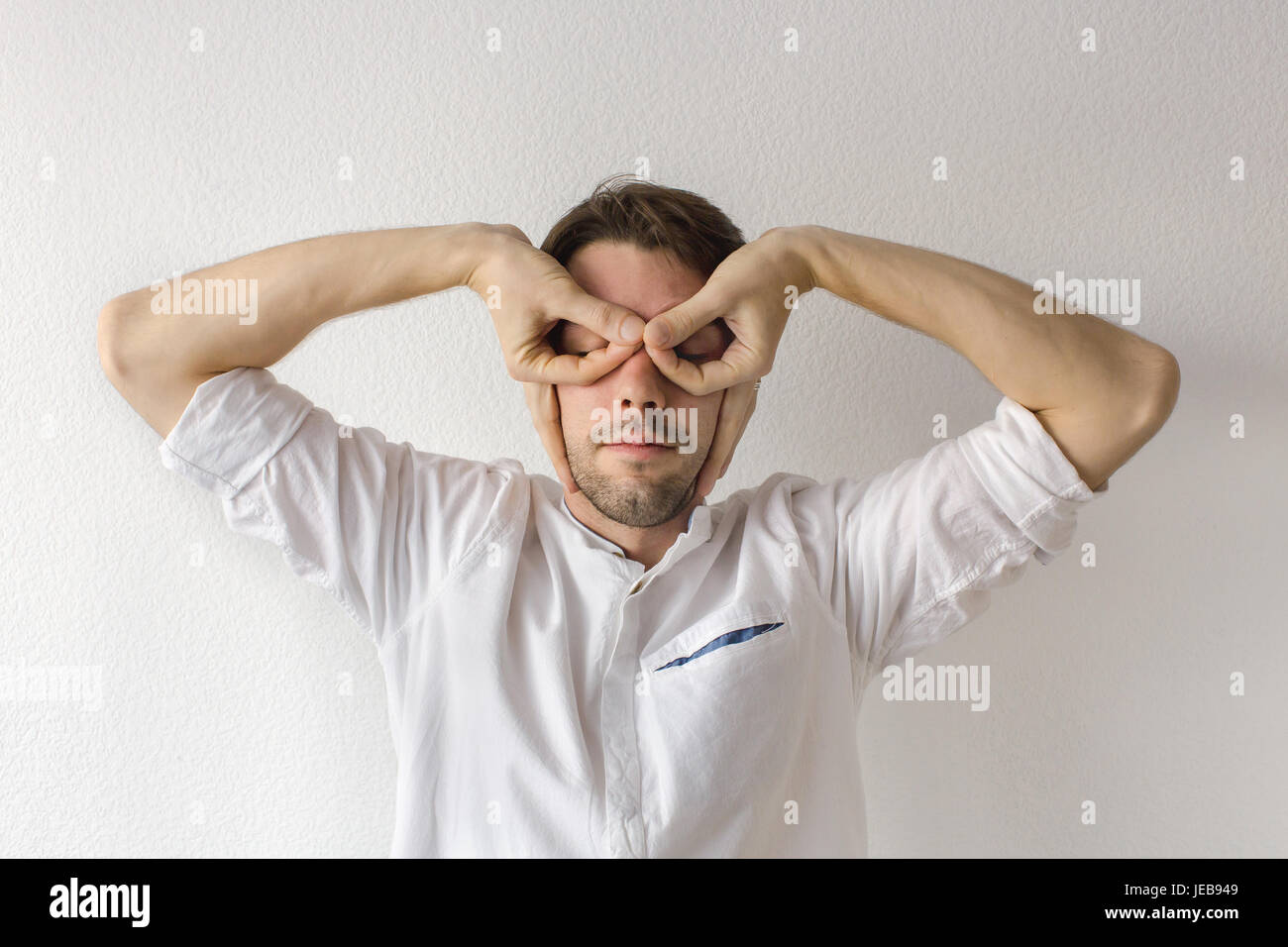 Young man closed his eyes with his hands Stock Photo