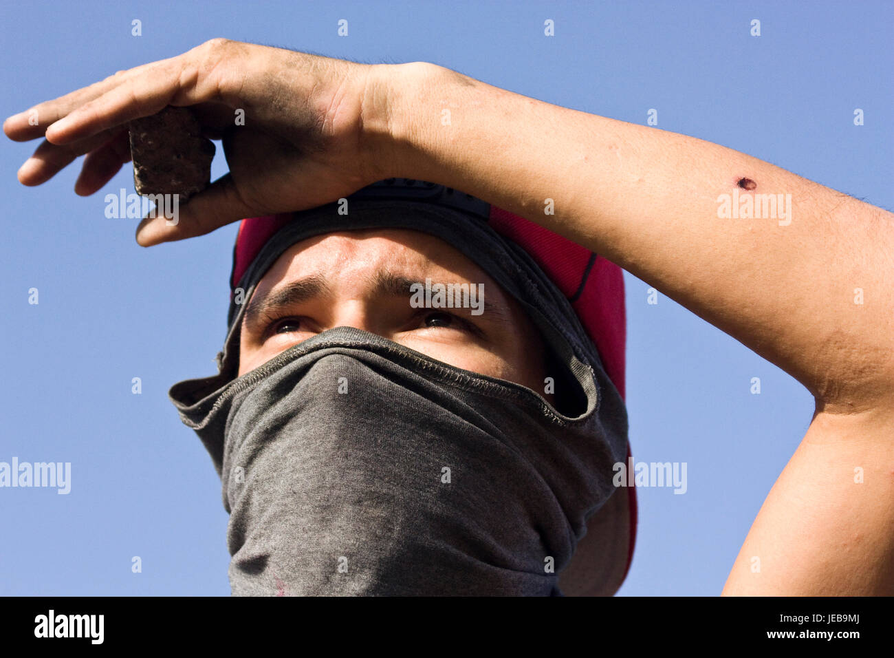 A young protester standing on a highway with his face covered. Stock Photo