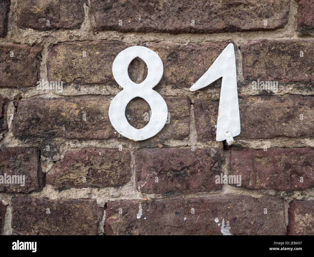 White house number 81 on an old brick wall, close-up Stock Photo