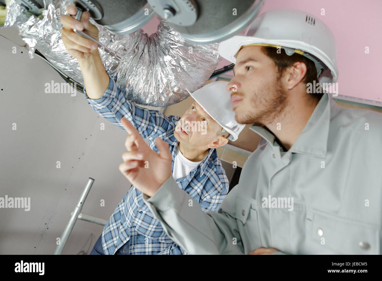 builders working on ventilation system Stock Photo - Alamy