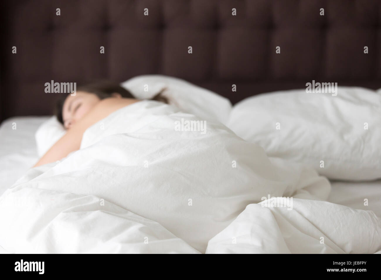 Woman sleeping alone on large double bed Stock Photo