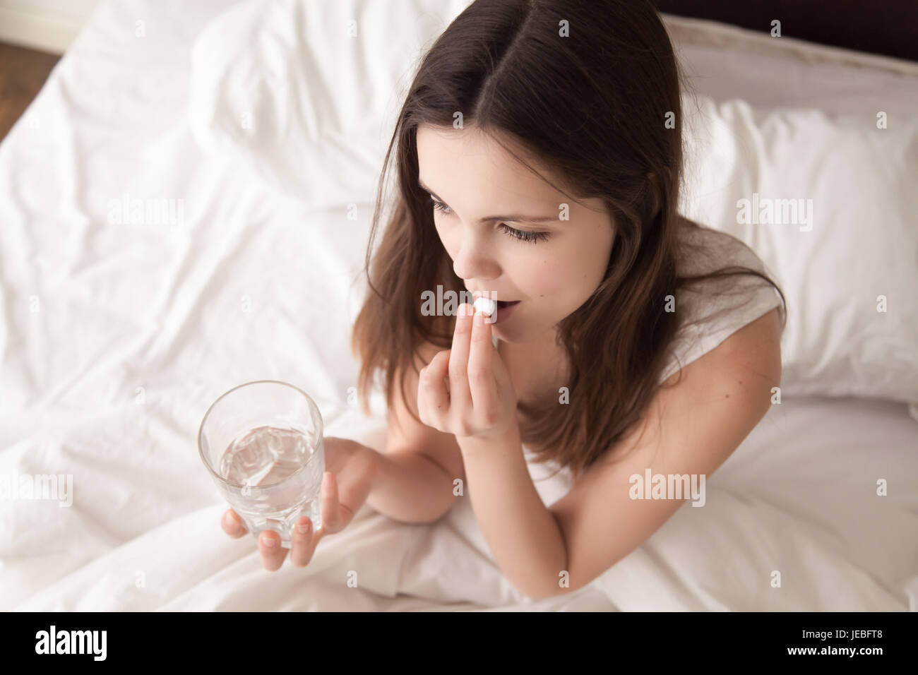 Sick woman drinking pill in bed in the morning Stock Photo