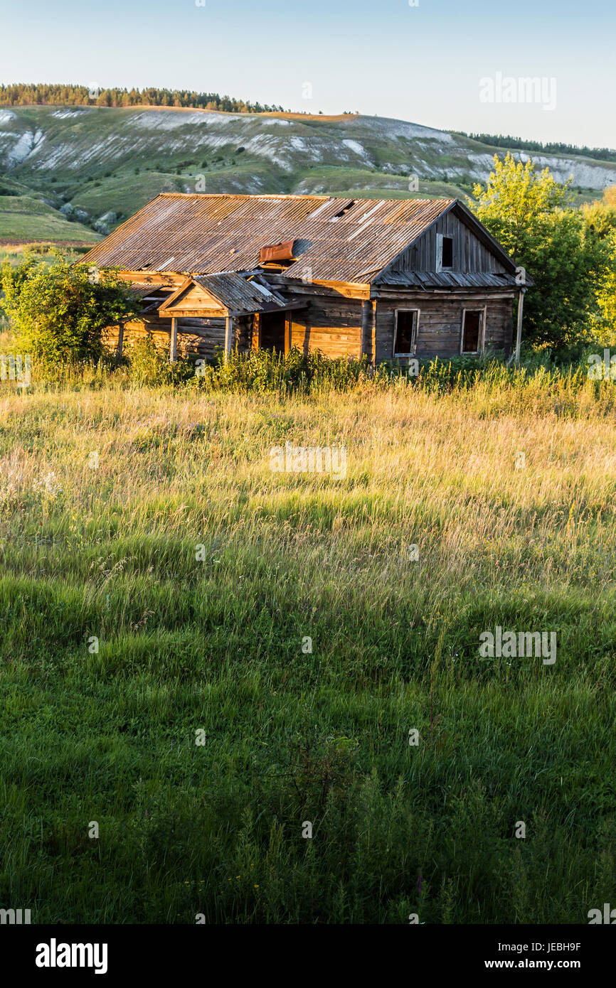 Old abandoned wooden house, overgrown grass on a bright sunny summer