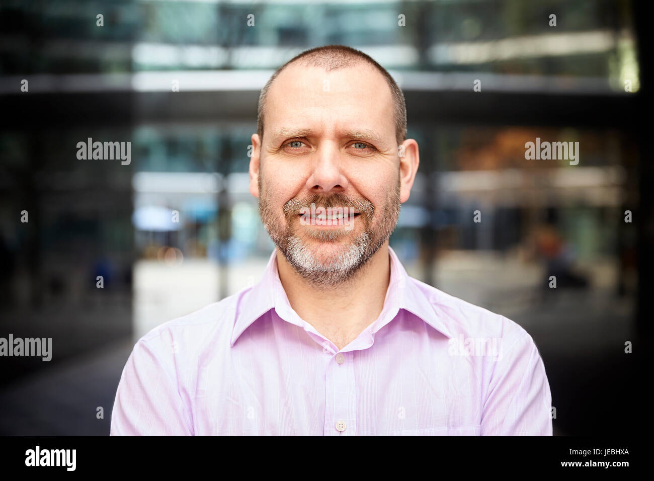 Portrait of pleasant businessman is standing in front of the building