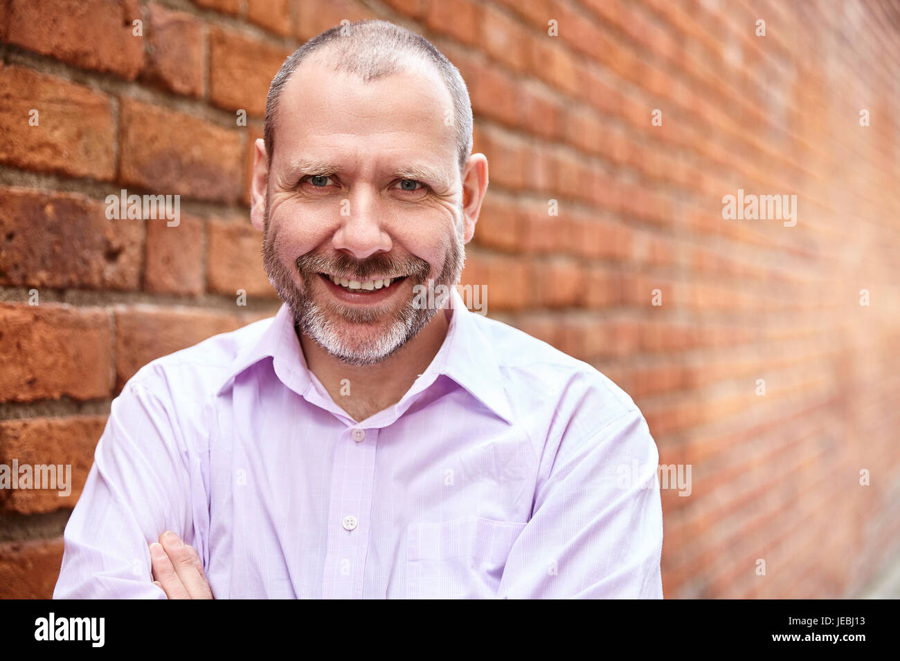 Portrait of smiling man against a brick wall background Stock Photo - Alamy