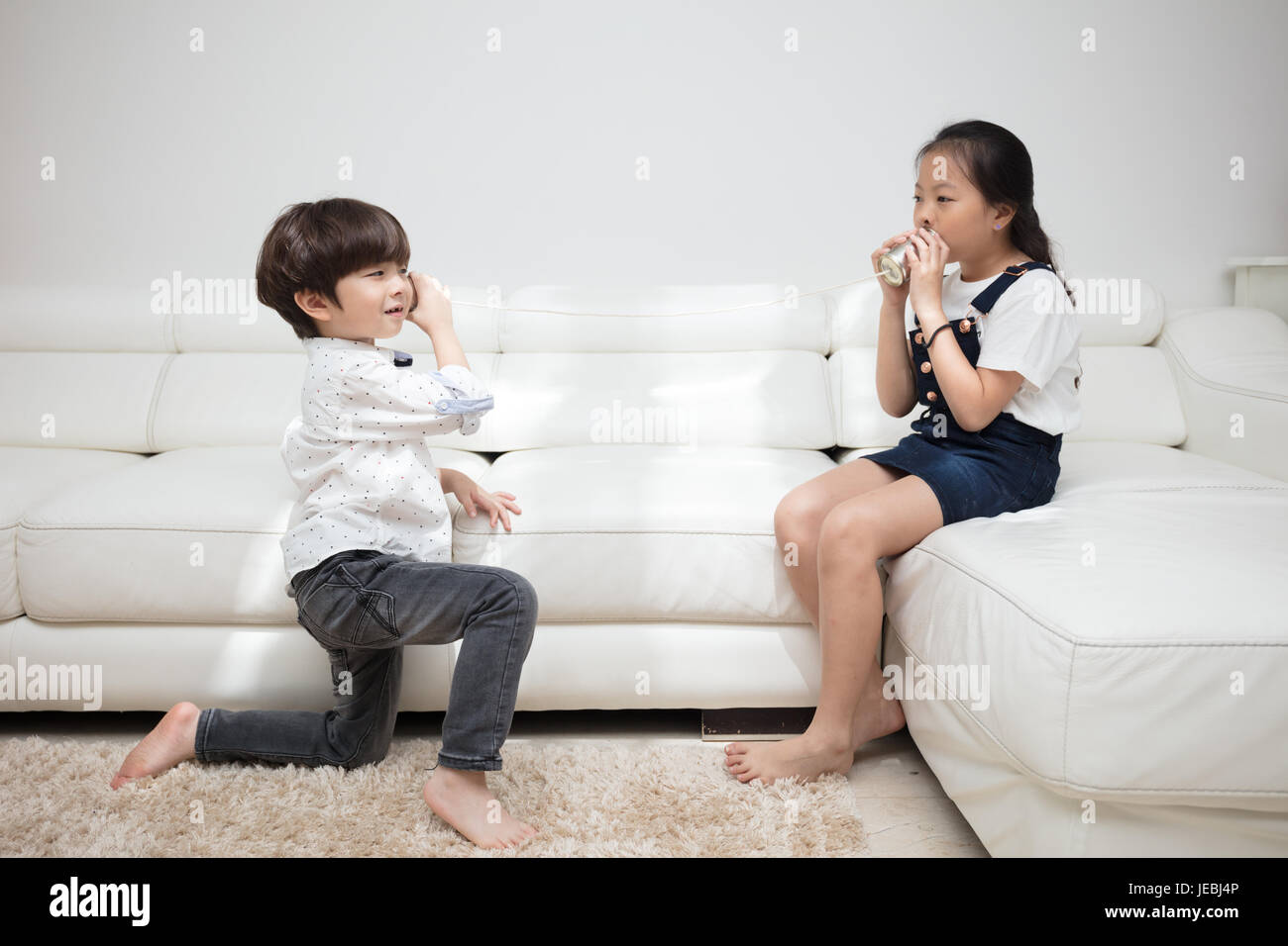 Asian Chinese little brother and sister playing tin can phone in the