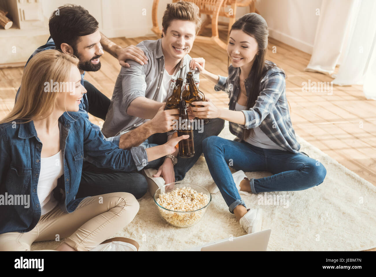 Two young couples watching movie on laptop while drinking beer and