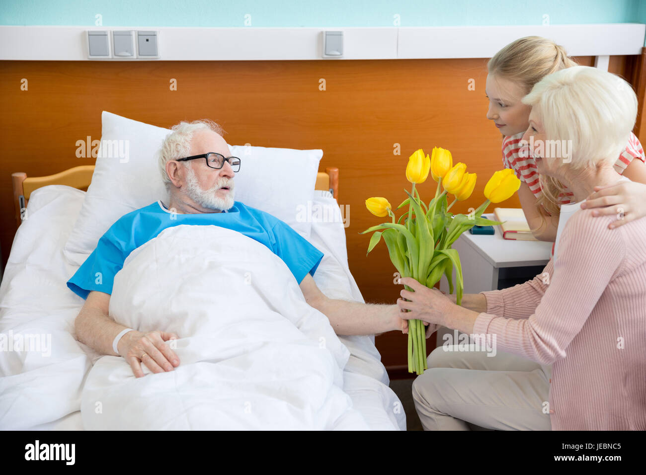 grandmother and granddaughter with tulip flowers visiting patient in