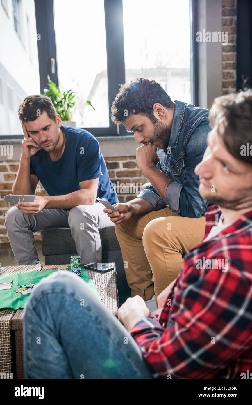 young men playing cards at gaming table. young people having fun ...