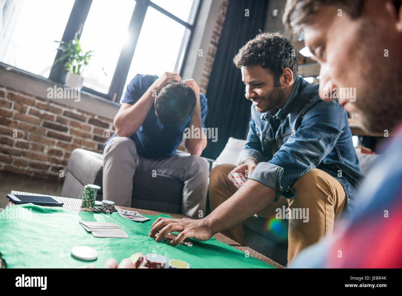 Young men playing cards at gaming table, young people having fun ...