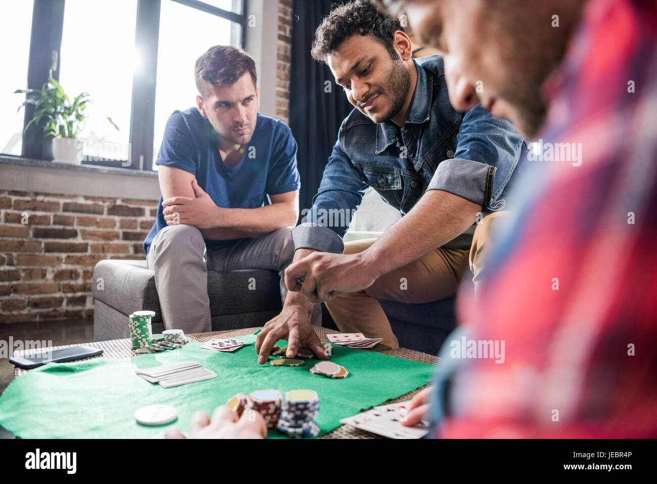Young men playing cards at gaming table, young people having fun ...