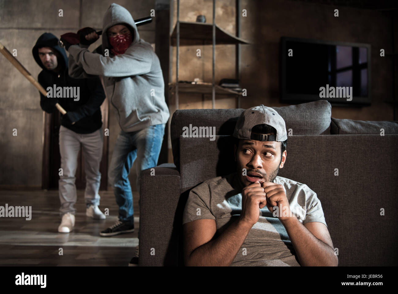 Scared man hiding behind sofa from burglars, house robbery scene Stock  Photo - Alamy