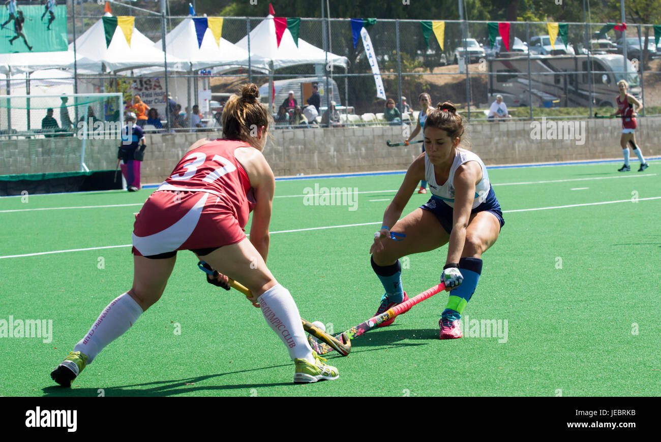 Two female field hockey players competing for the ball in a match