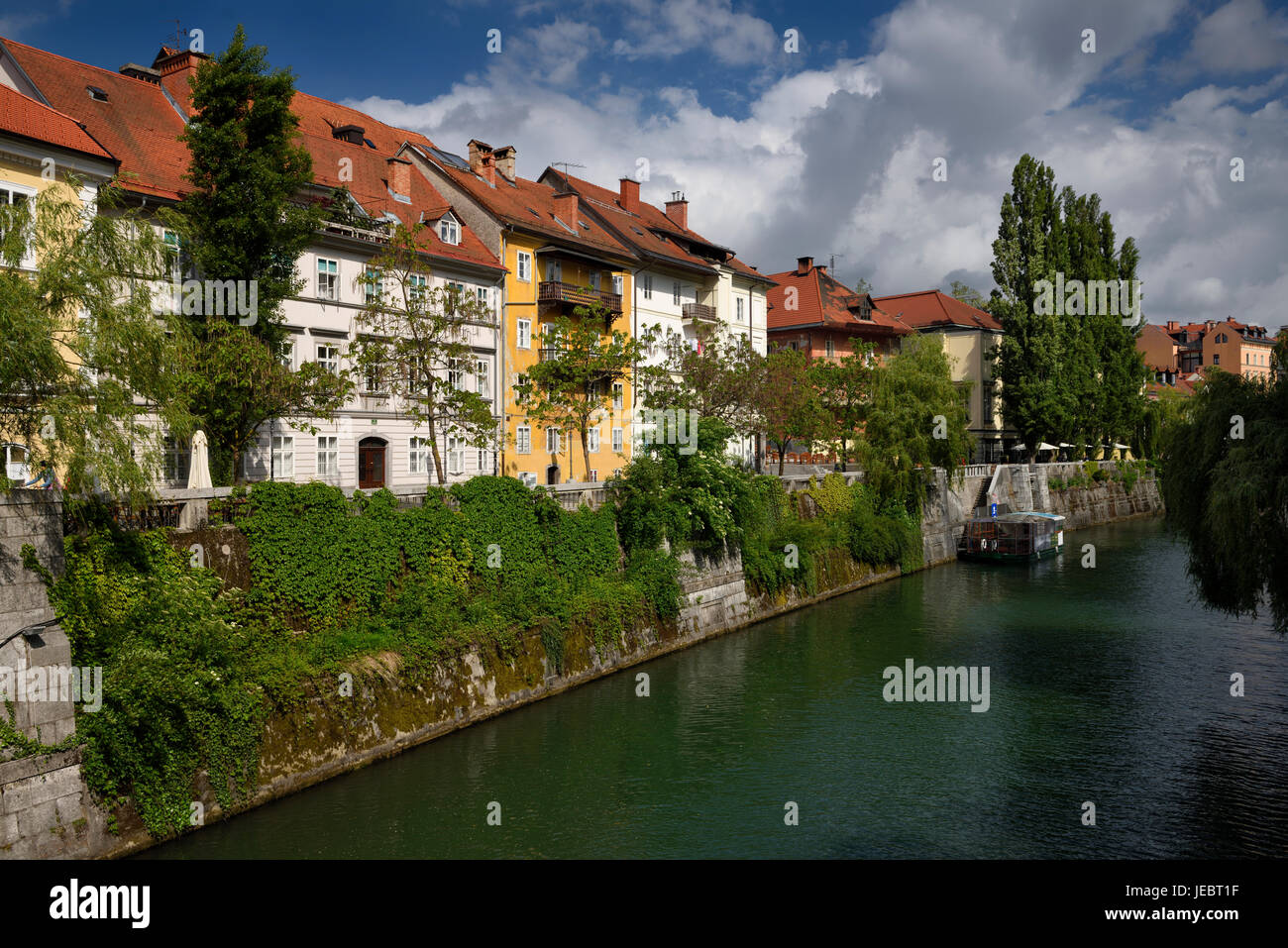 Historic houses on the ivy covered Hribar Quay embankment of the Ljubljanica river canal waterway in the old town of Ljubjlana Slovenia Stock Photo