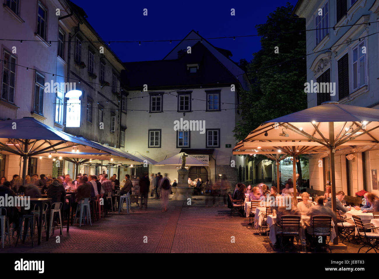 Nightlife outdoor restaurant cafes in Cobblestone Courtyard Ribji or Fish Square from Cankar Quay to Town Square in Old Town Ljubljana Slovenia Stock Photo