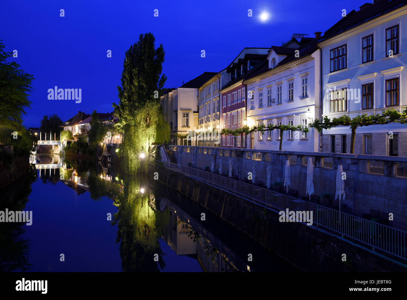 Cobblers Bridge and houses reflected on the calm Ljubljanica river canal in moonlight at dawn in Ljubljana Slovenia Stock Photo