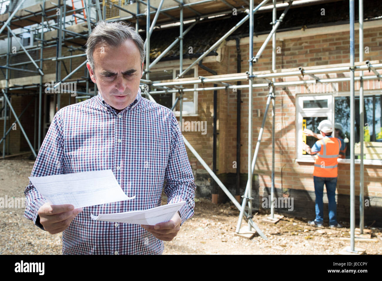Worried Client Looking At Bills For House Building Work Stock Photo