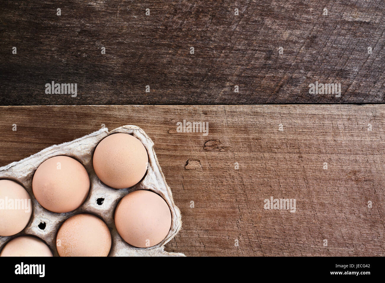 Farm fresh organic brown chicken eggs from free range chickens with in a paper carton over a rustic wooden background. Stock Photo