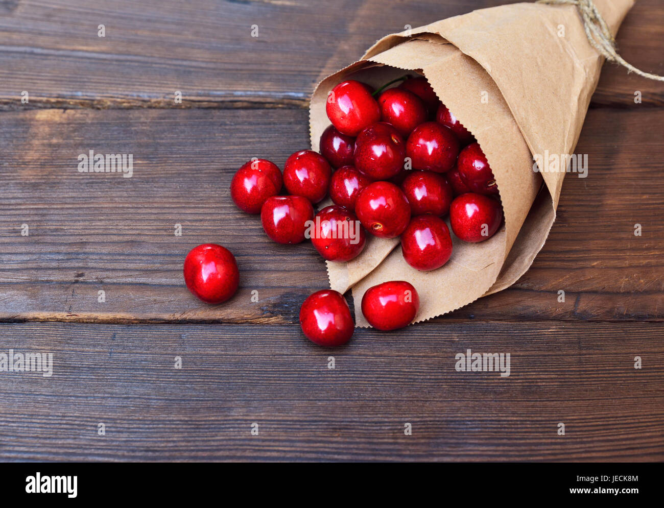 Red ripe cherry in a paper bag on a brown wooden background Stock Photo ...