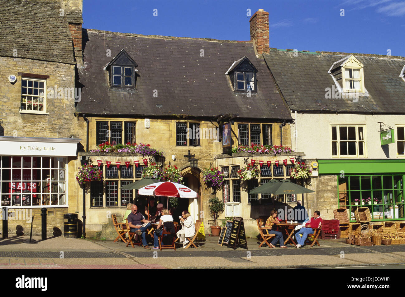 Great Britain, England, Oxfordshire, Cotswolds, Burford, street cafe, guests, no model release, Europe, destination, town, building, houses, terrace, architecture, cafe, bar, gastronomy, outside, sunny, people, rest, leisure time, street bar, floral decoration, sunshades, Stock Photo