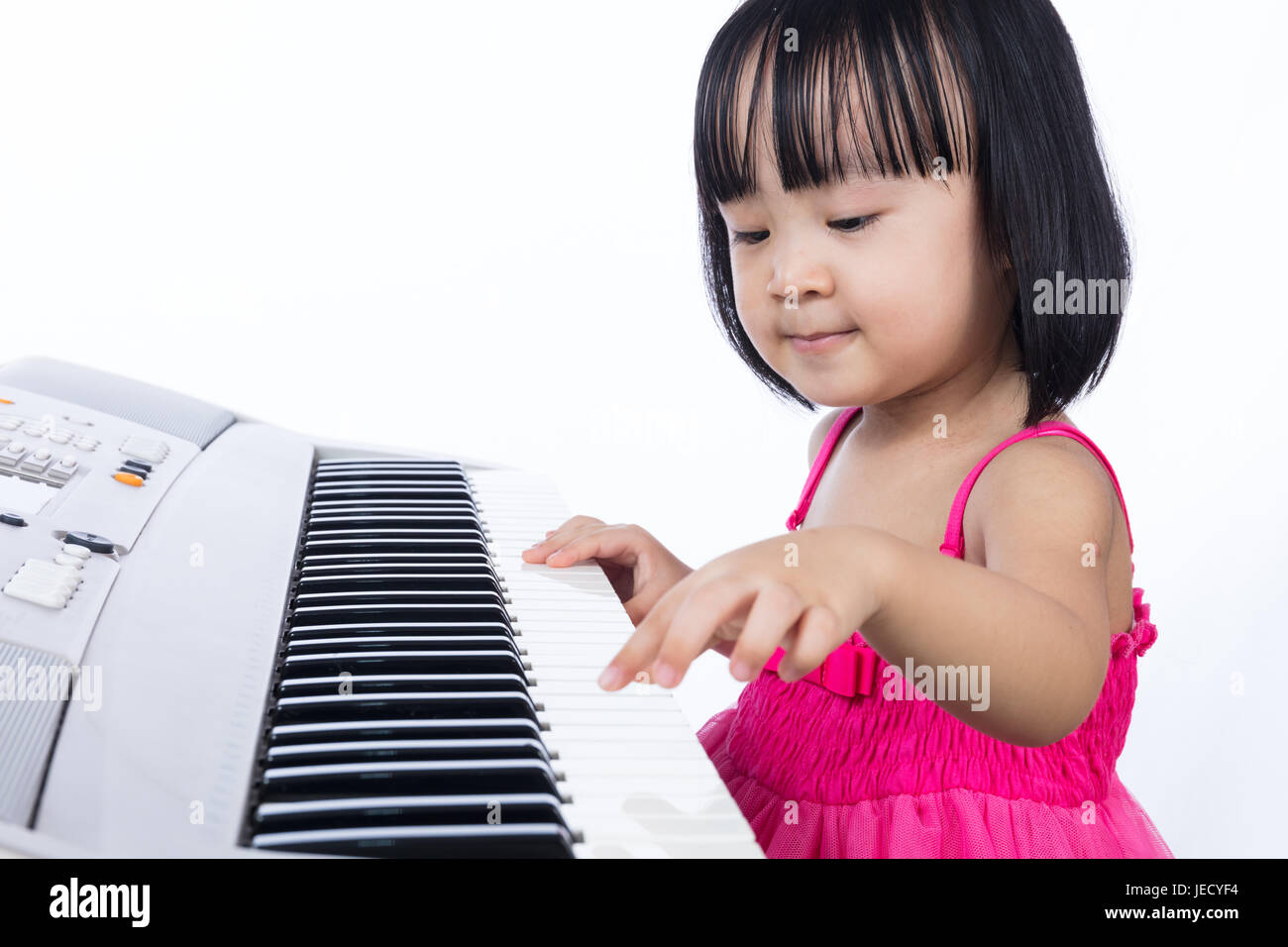 Asian Chinese little girl playing electric piano keyboard in the living room at home. Stock Photo