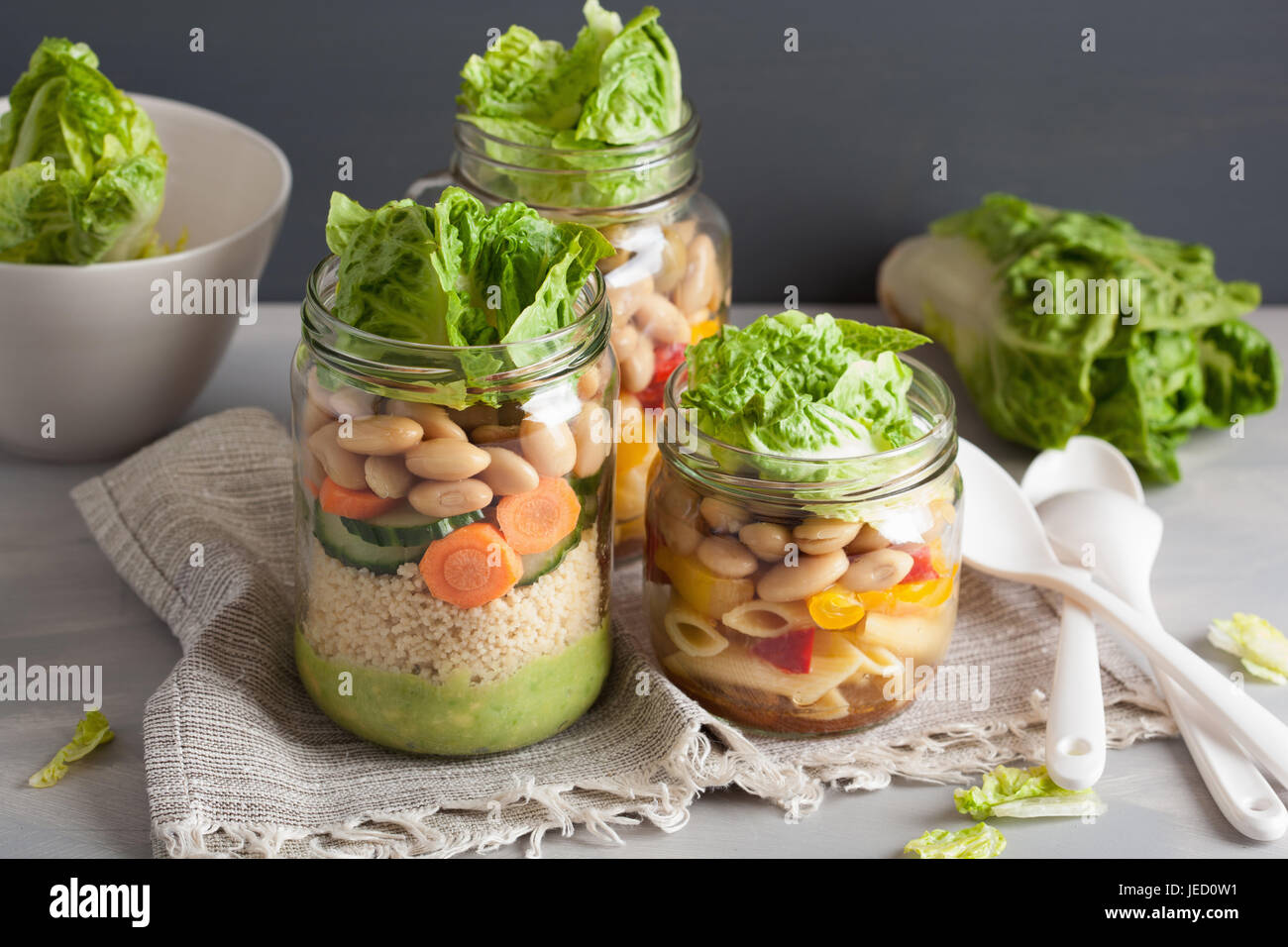 vegan couscous and pasta salad in mason jars with vegetables beans
